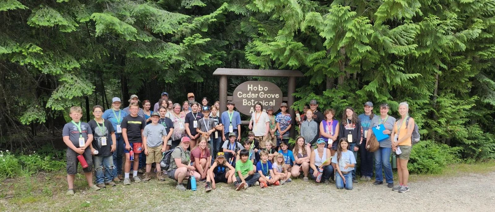 Group of young people gathered around public land sign.
