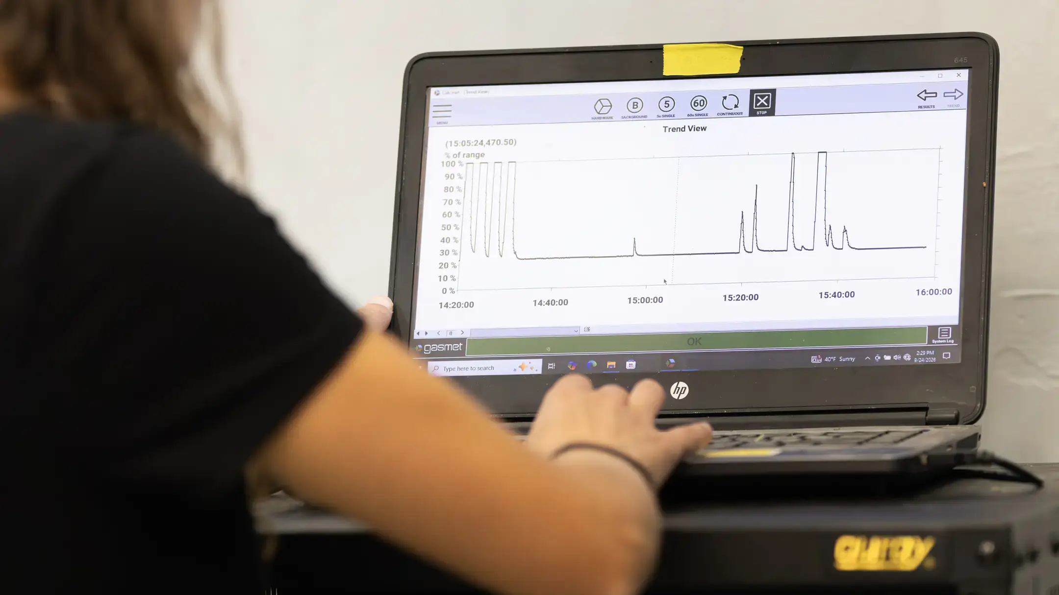 Person using a laptop to monitor a trend graph with fluctuating data readings.