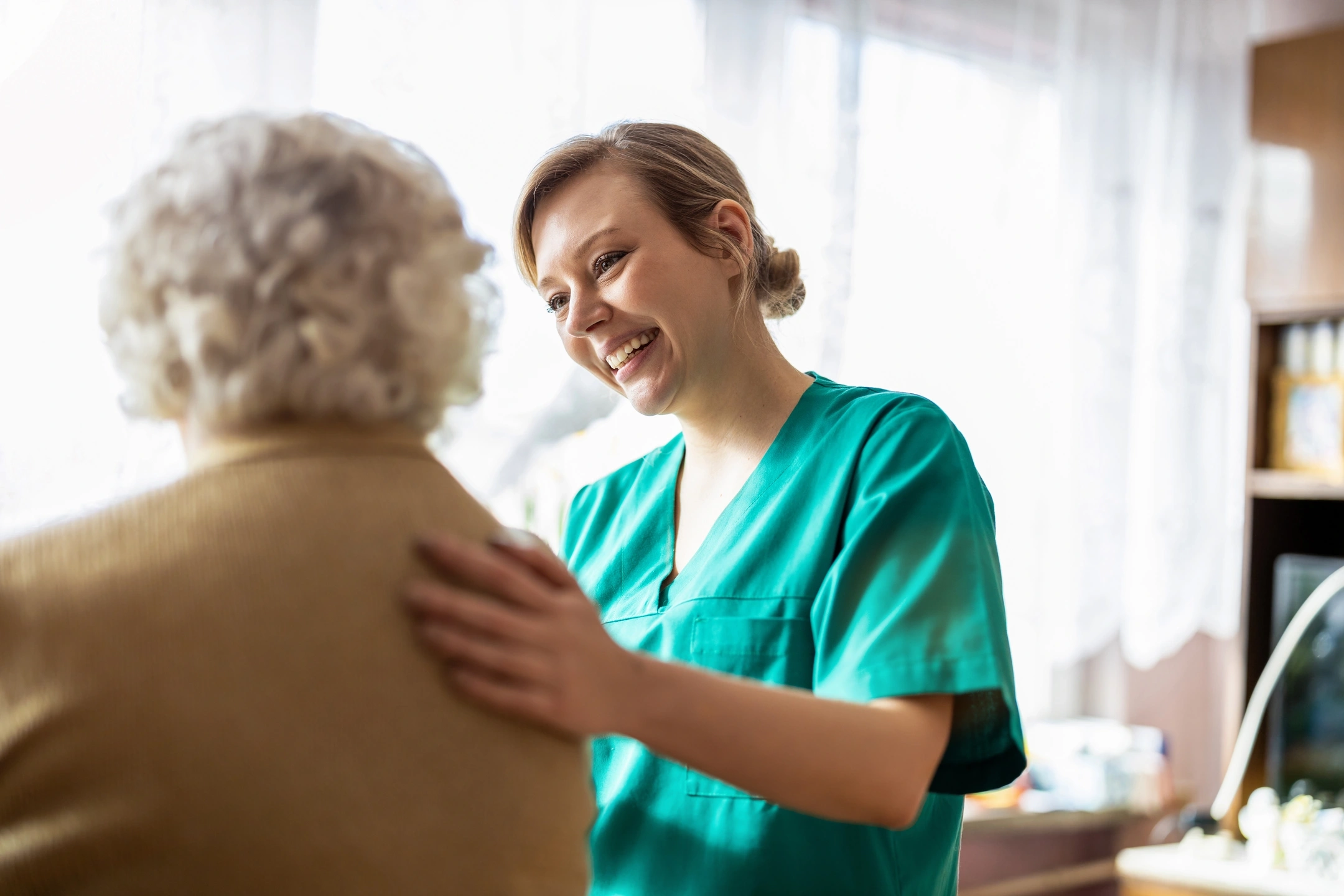 A caregiver smiling at an elderly patient.