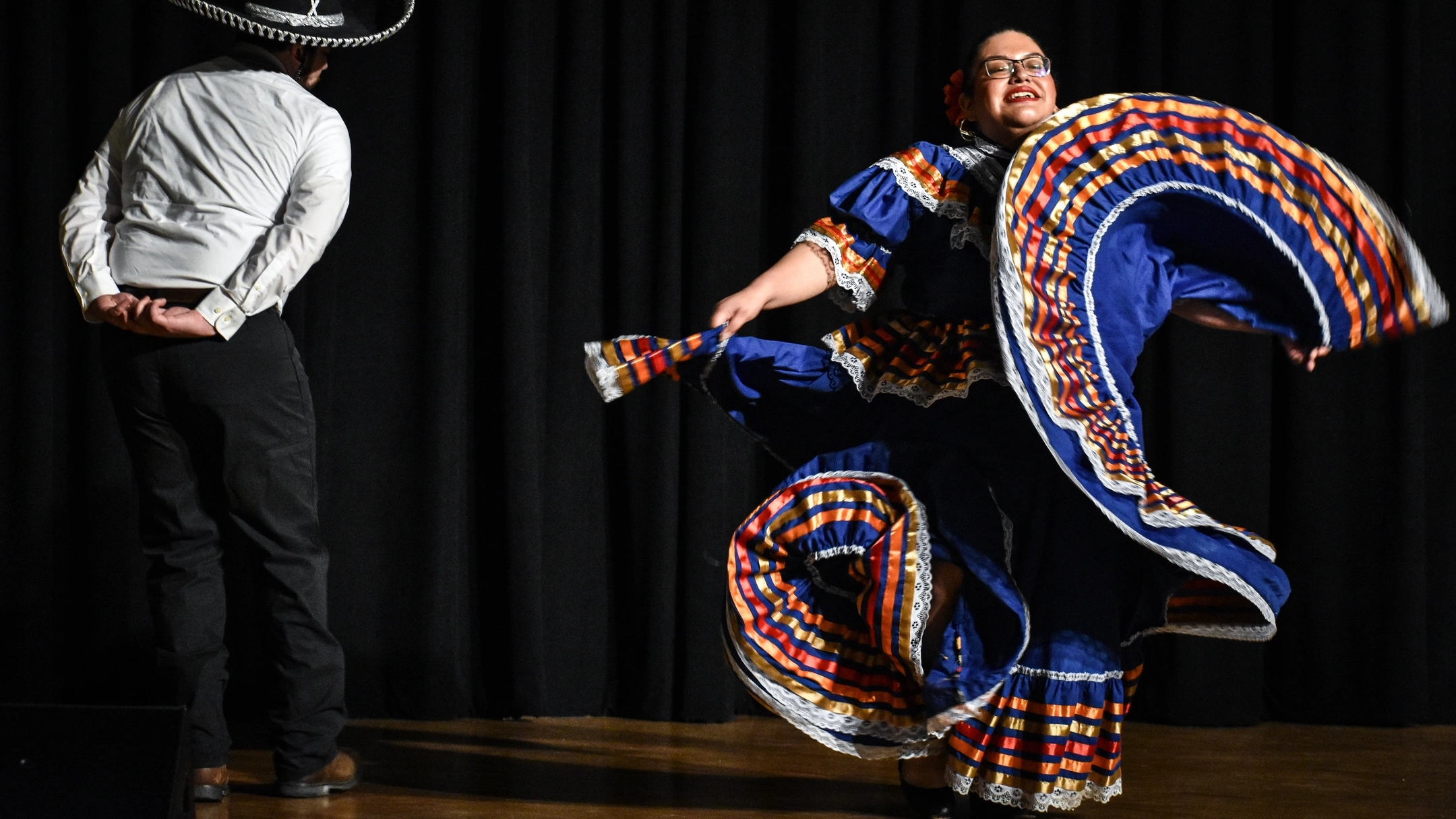 Two people dancing on stage in cultural attire