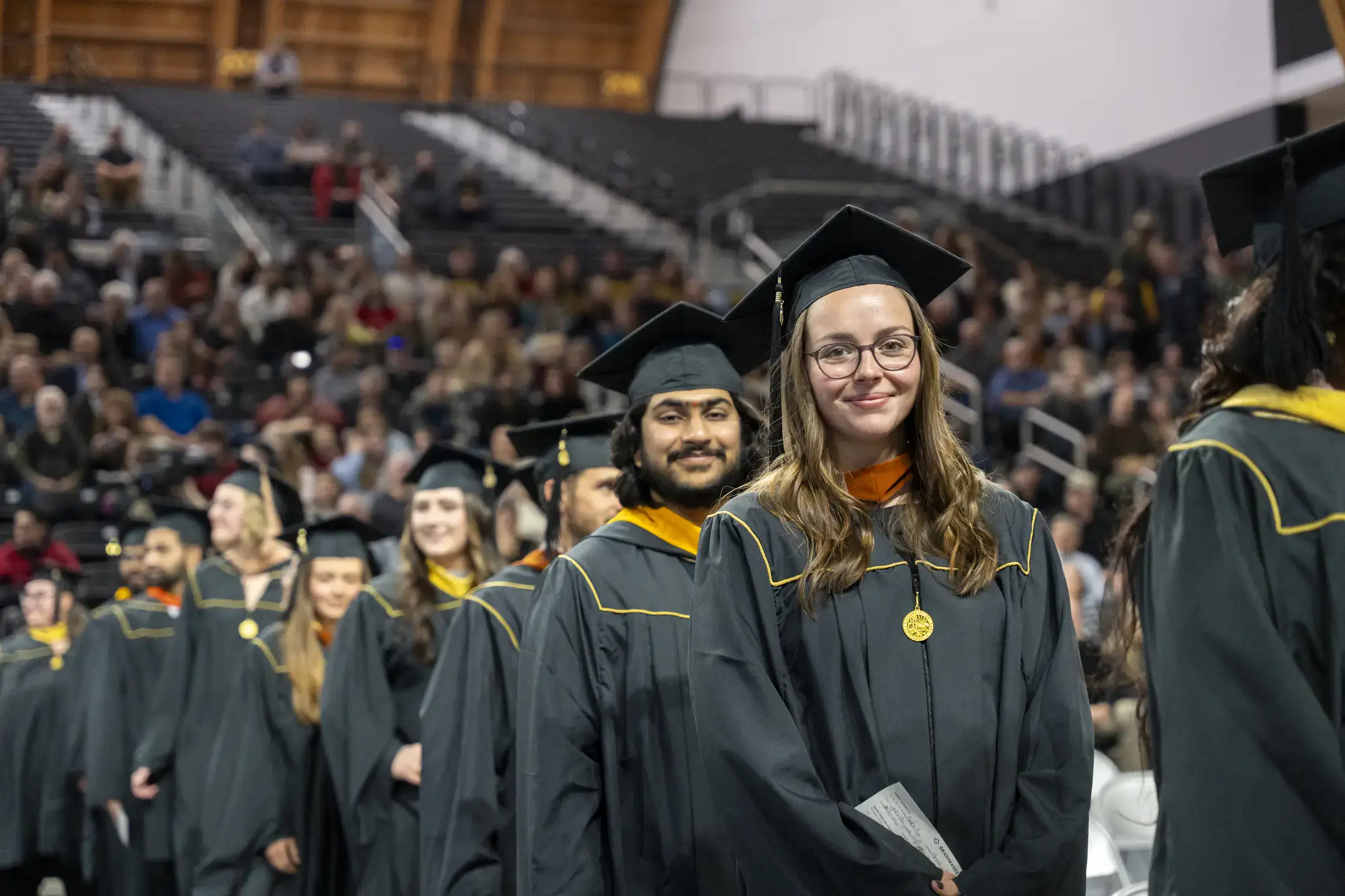 People in a line wearing graduation regalia. 