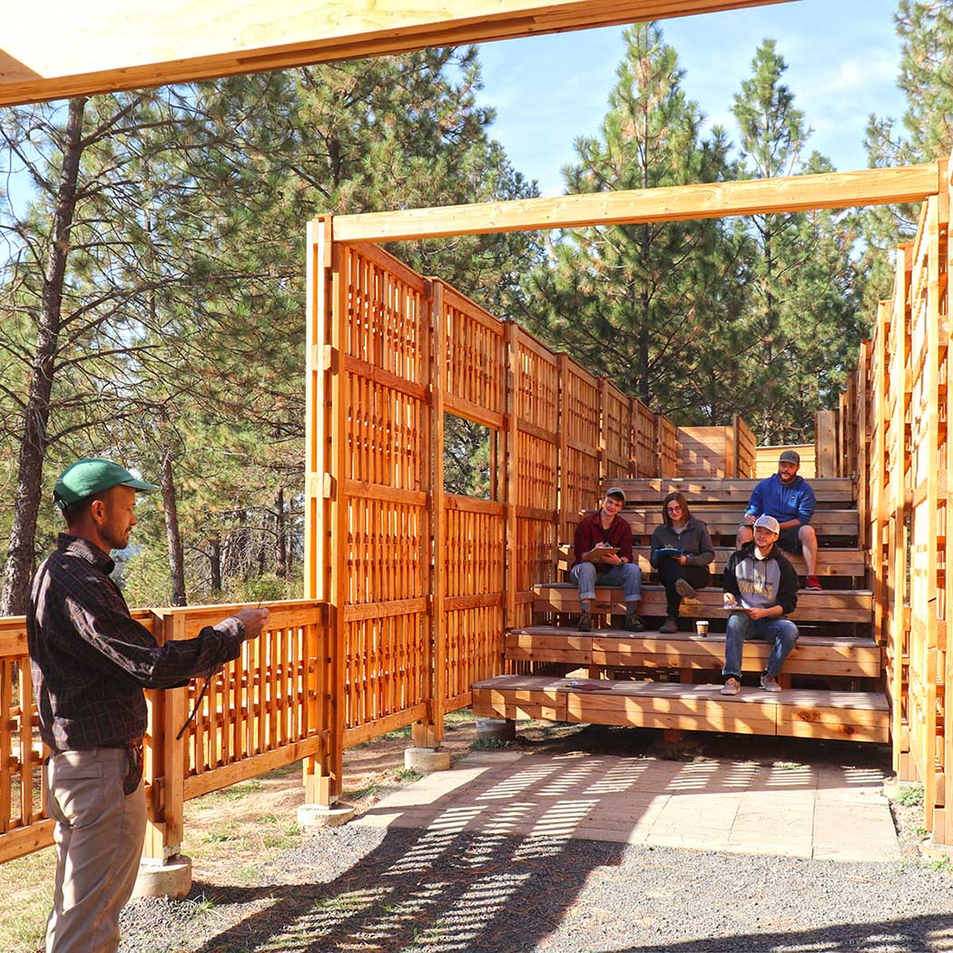 Speaker presents to students sitting on the pavilion.
