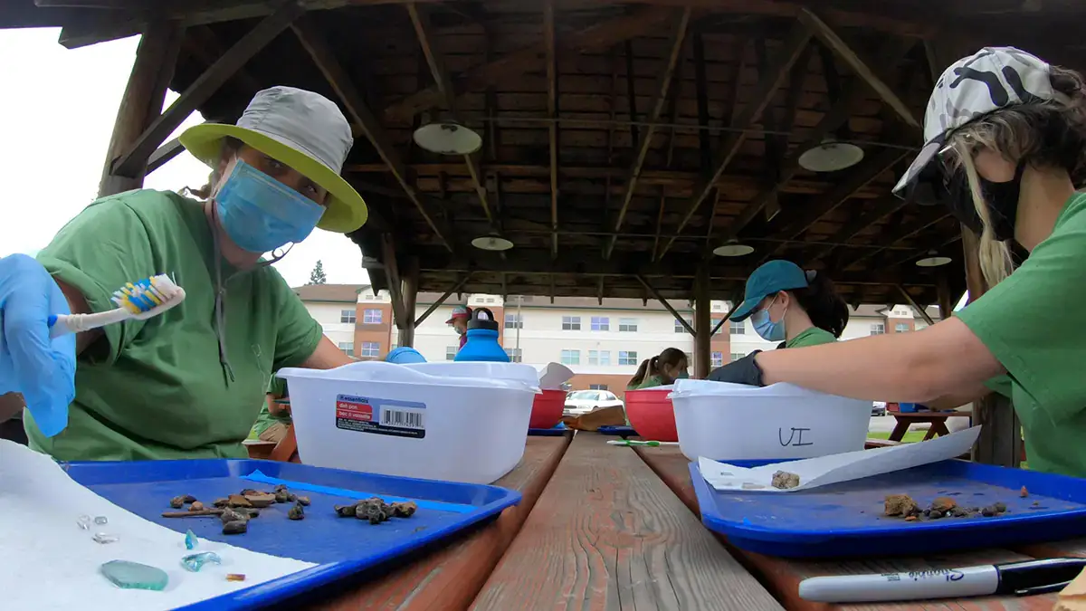 Two people pick through findings an archaeological dig.
