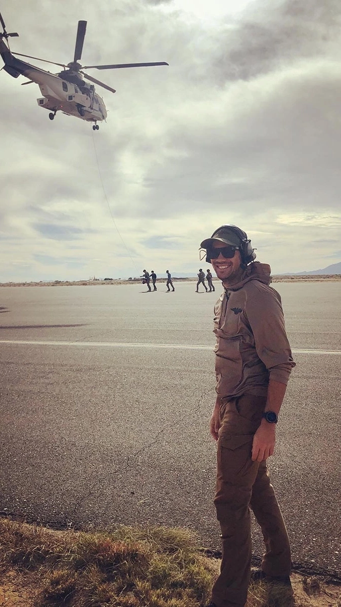 Man wearing sunglasses and headphones underneath helicopter