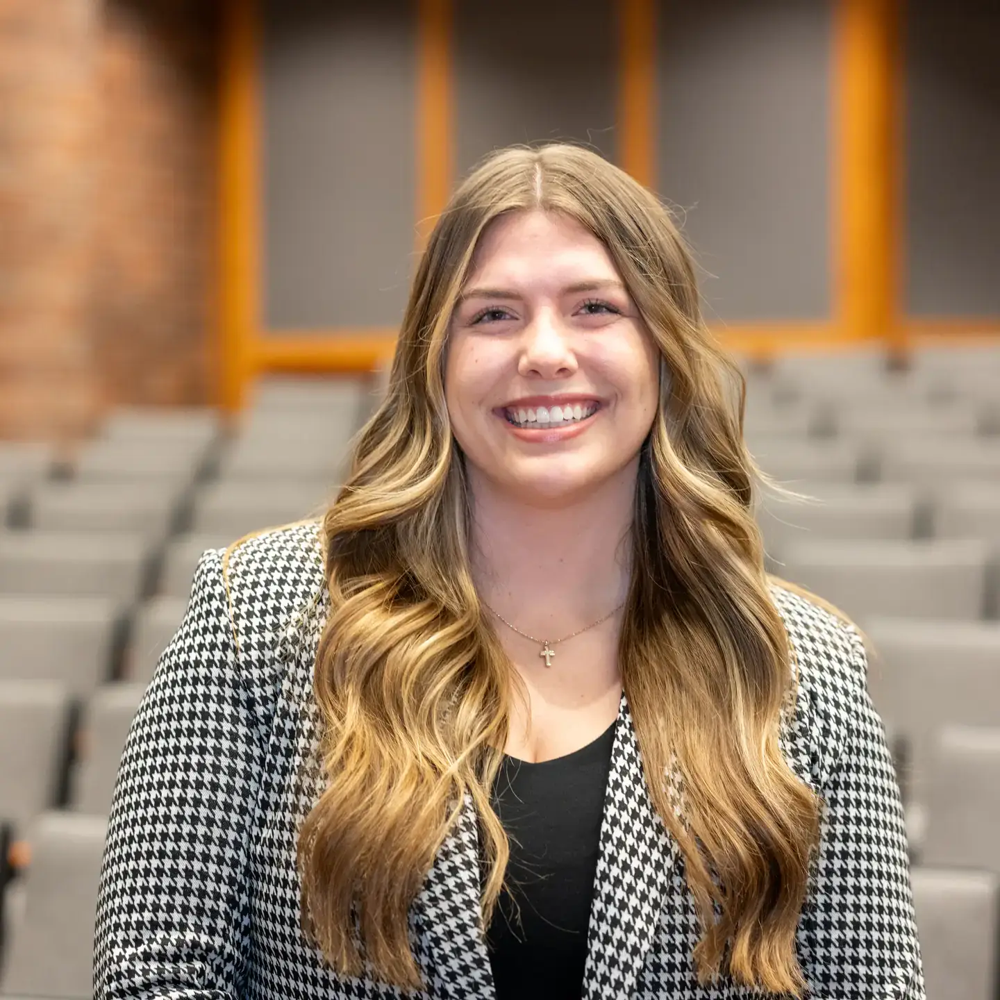 Smiling woman stands in law school lecture hall.
