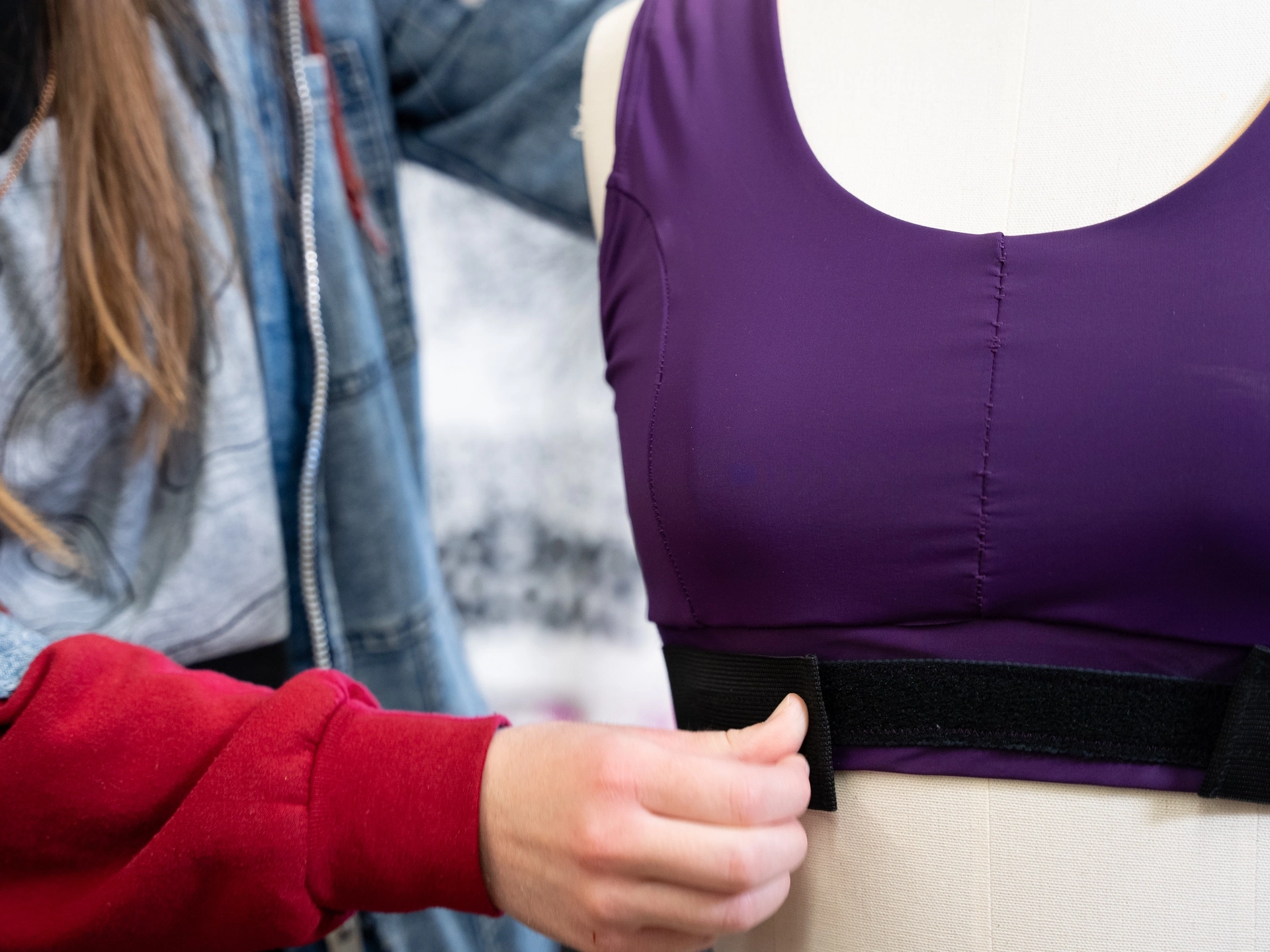 A person adjusts the straps of a sports bra on a mannequin.