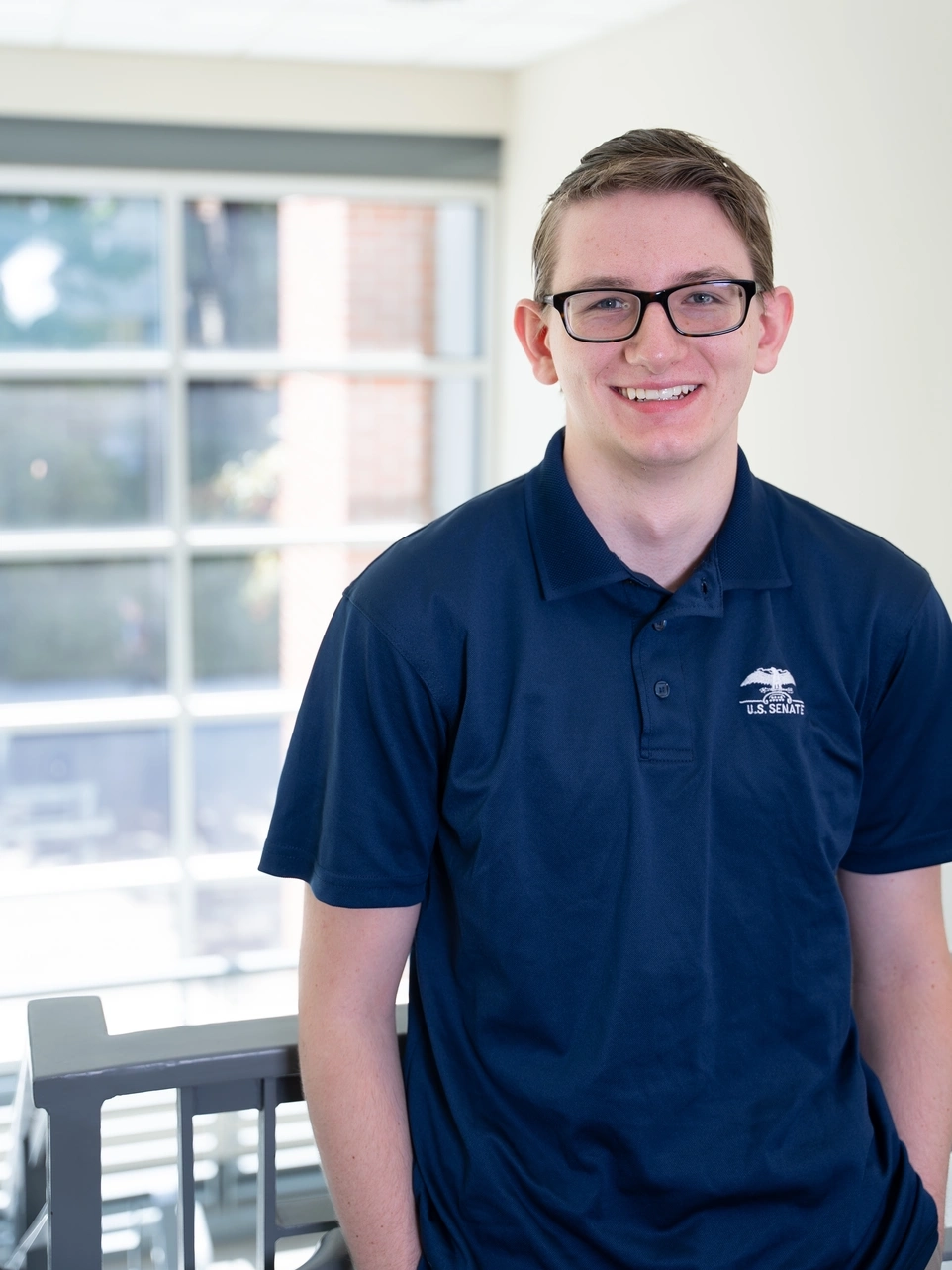 Austin Smith leaning on a staircase railing smiling