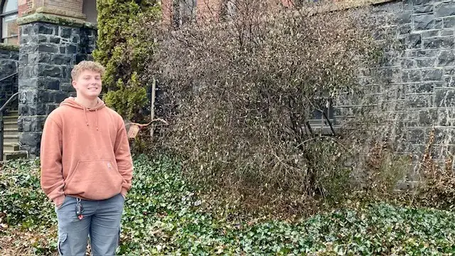 Photo of man wearing orange hoodie in front of building