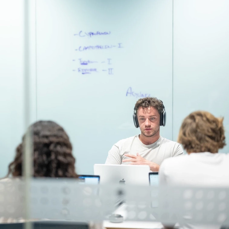 Students work in a small classroom full of whiteboards