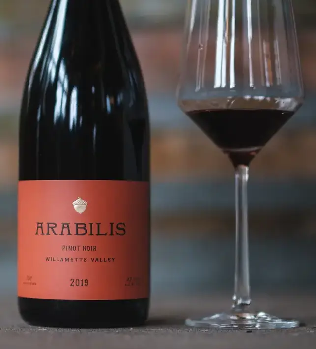 A wine bottle and glass sitting on a table.