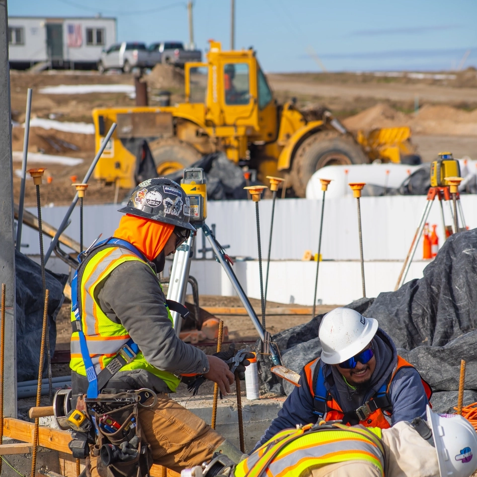 Three construction workers building a foundation to a building