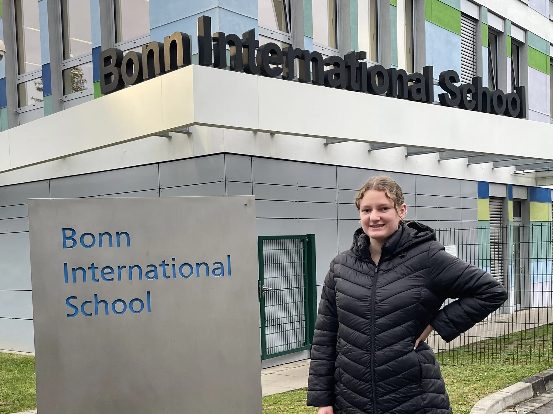 Christina Petrie standing in front of the Bonn International School building