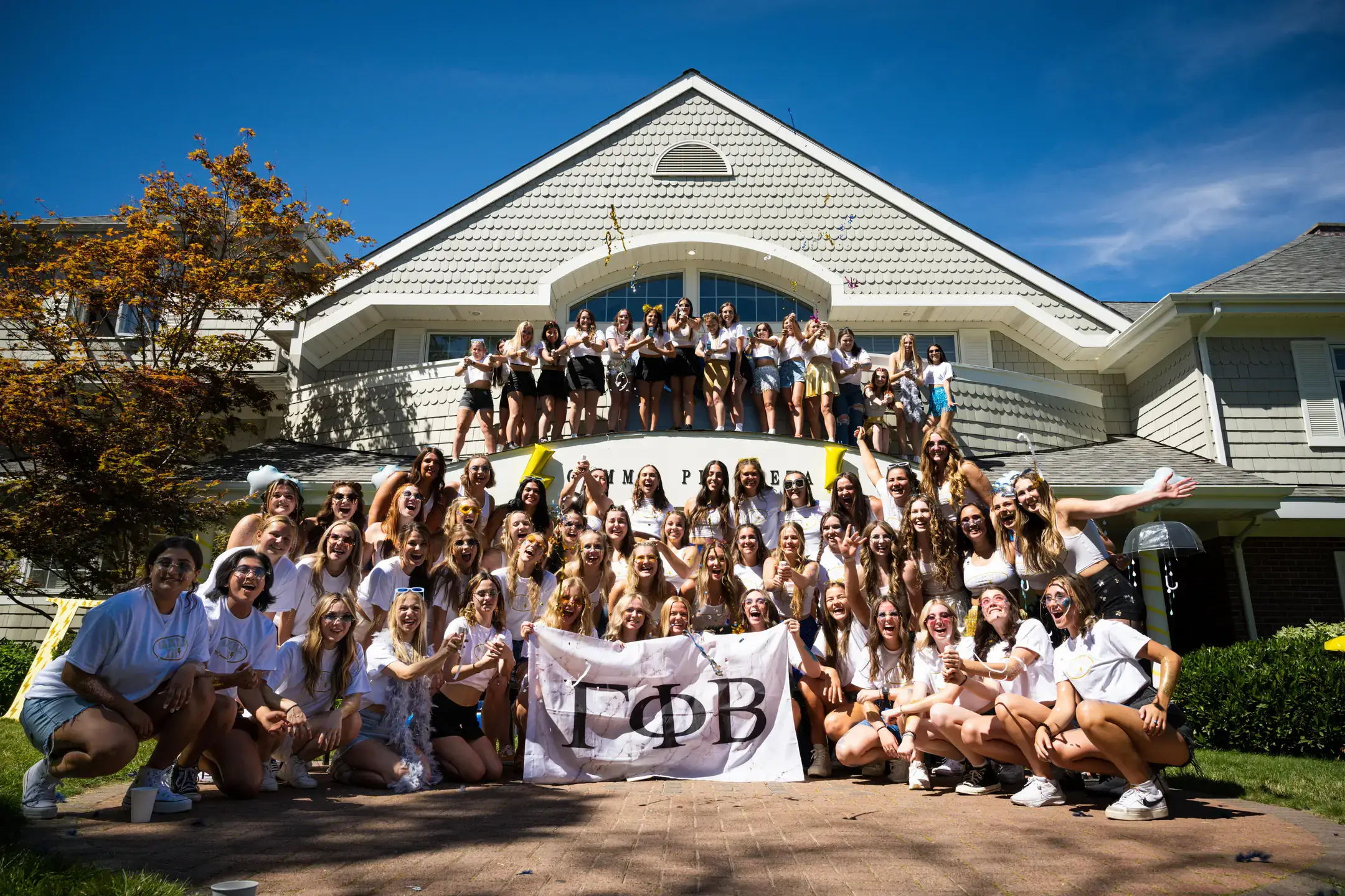 Sorority members holding their flag in front of their sorority house.