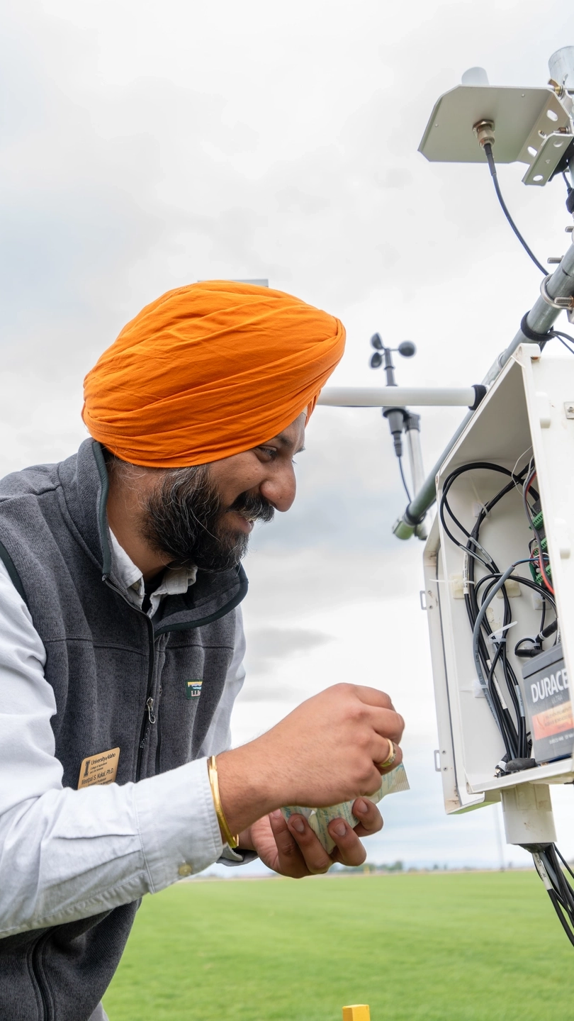 Meetpal Kukal studies wiring inside of a white box at one of his SnakeFlux weather stations, based in a Nampa sod field.