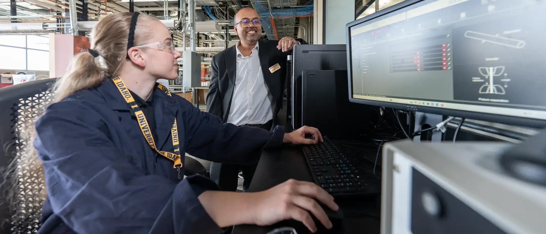 A person engages with scientific software on a monitor in a laboratory, while another individual observes.