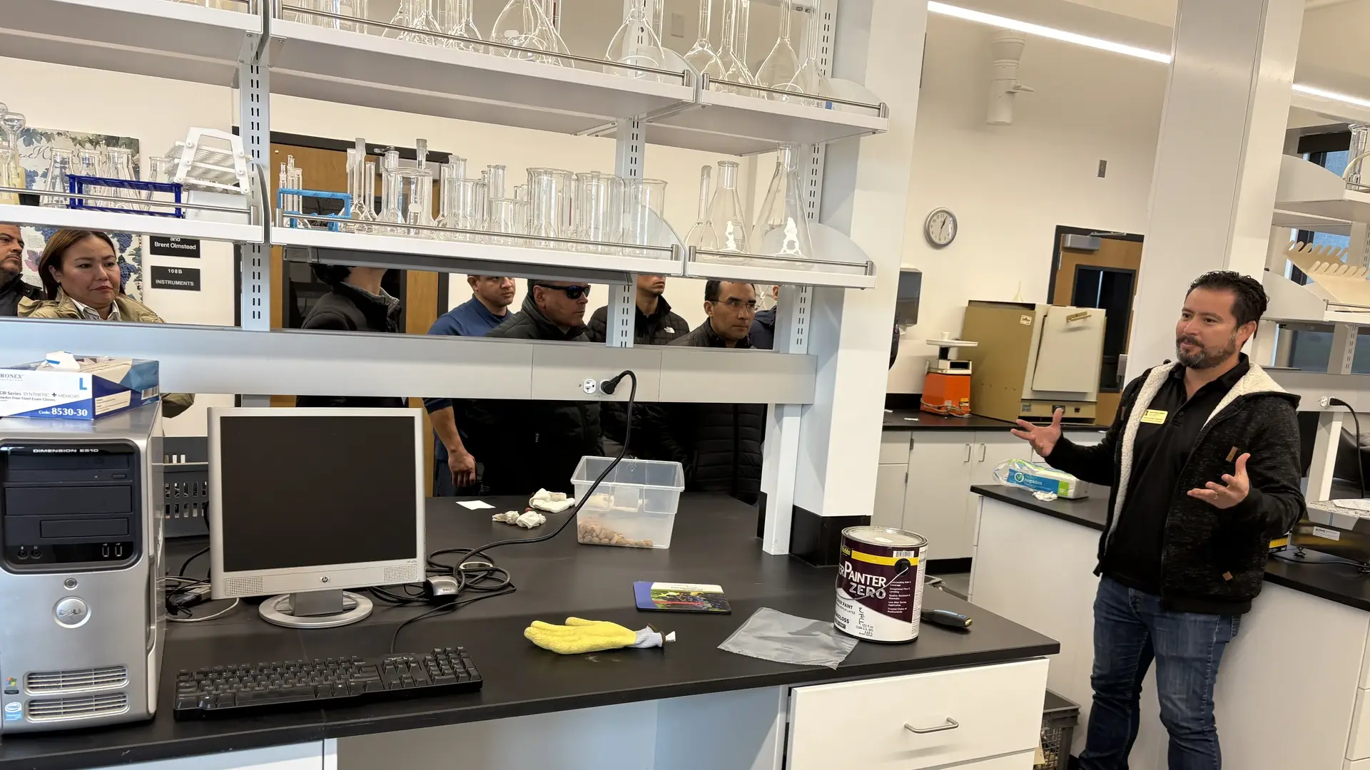 A presenter talks in a laboratory room while chefs from several countries listen.