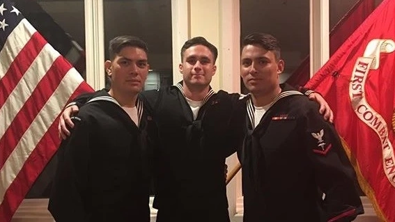 Three men stand between two flags