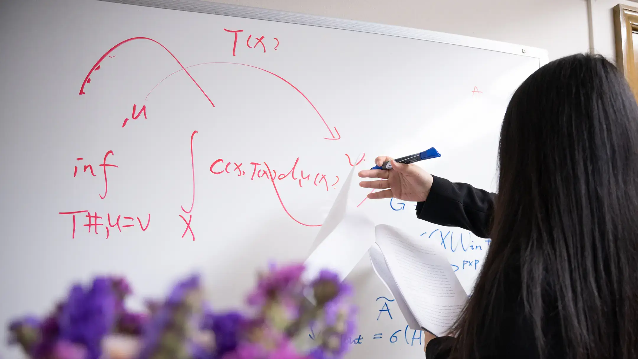 University of Idaho Mathematics and Statistical Science faculty Tiantian Yang uses a white board to work on mathematical models of diseases that can reduce healthcare costs and that can be easy to interpret so they are trusted by healthcare workers.