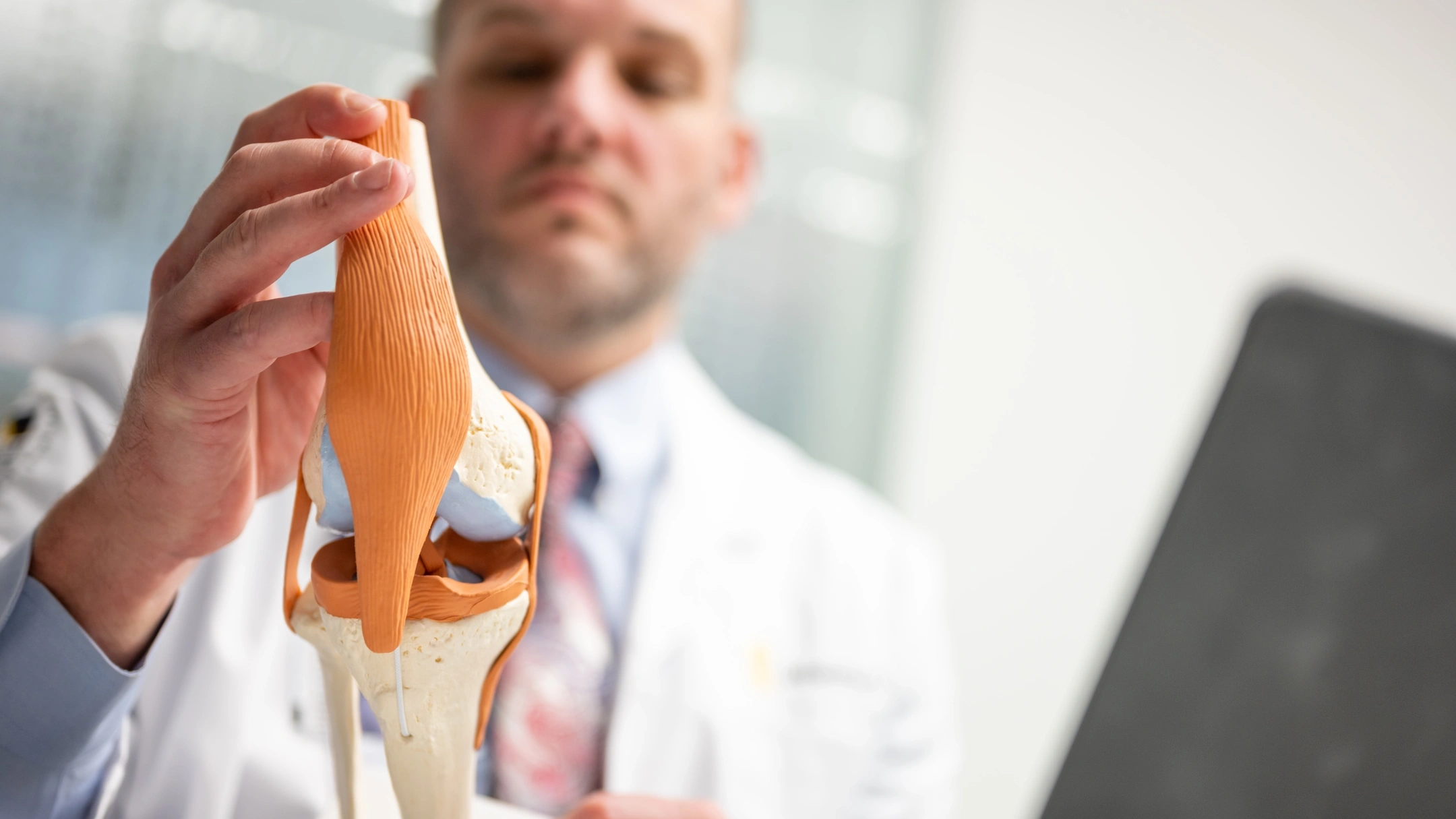 Bryan Jones holds a model of a knee.