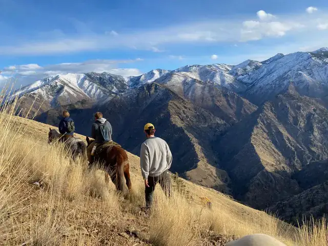 People ride horses in front of mountains
