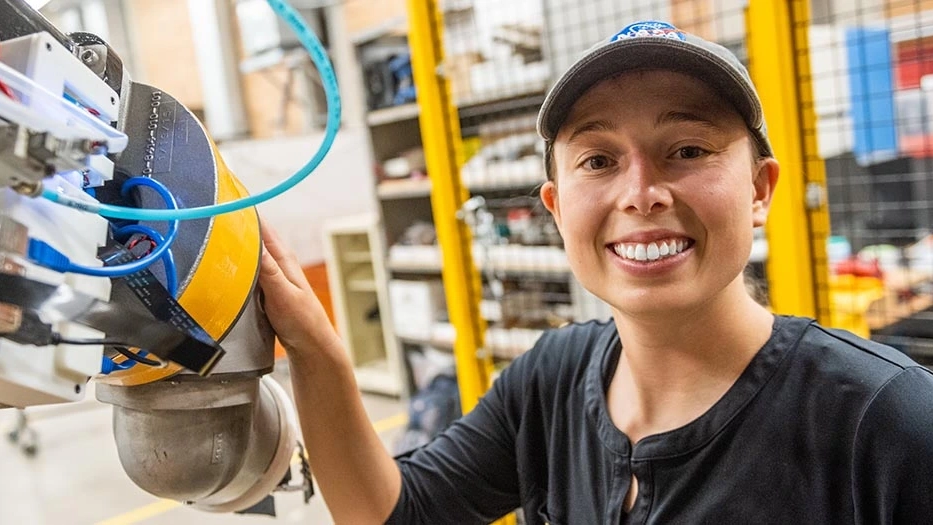 A smiling woman next to robotics machinery