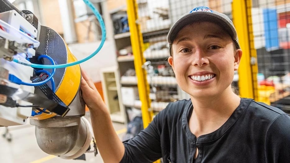A smiling woman next to robotics machinery