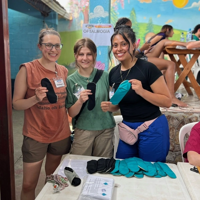Three women holding up menstrual pads