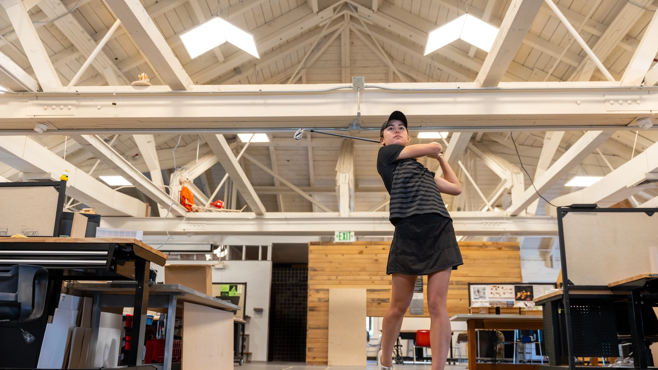 Jenna Bruggeman swings a golf club in the College of Art and Architecture South Building.