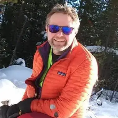 Jim Ekins wear an orange coat and sunglasses