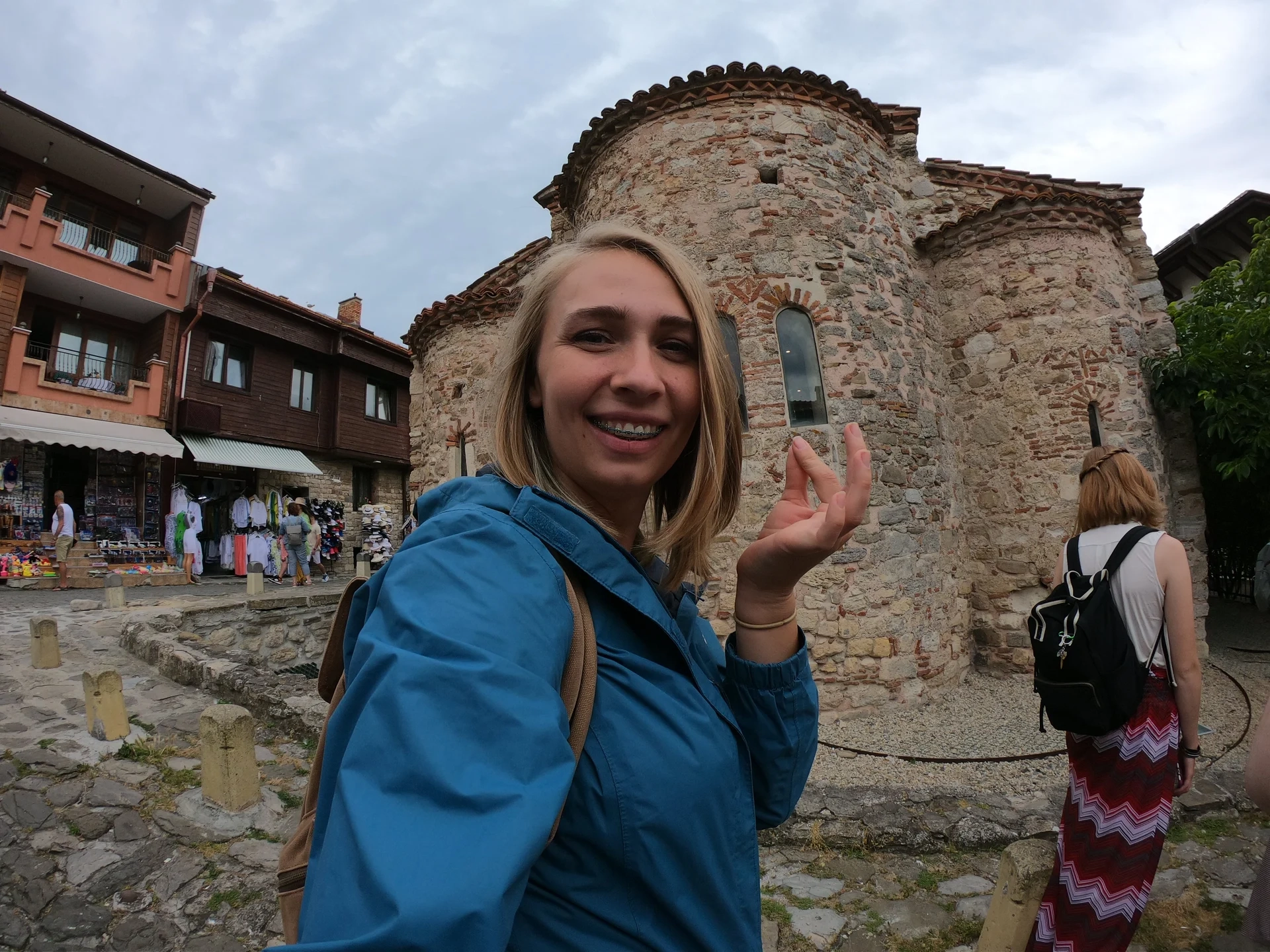 Woman waves while walking past an ancient temple