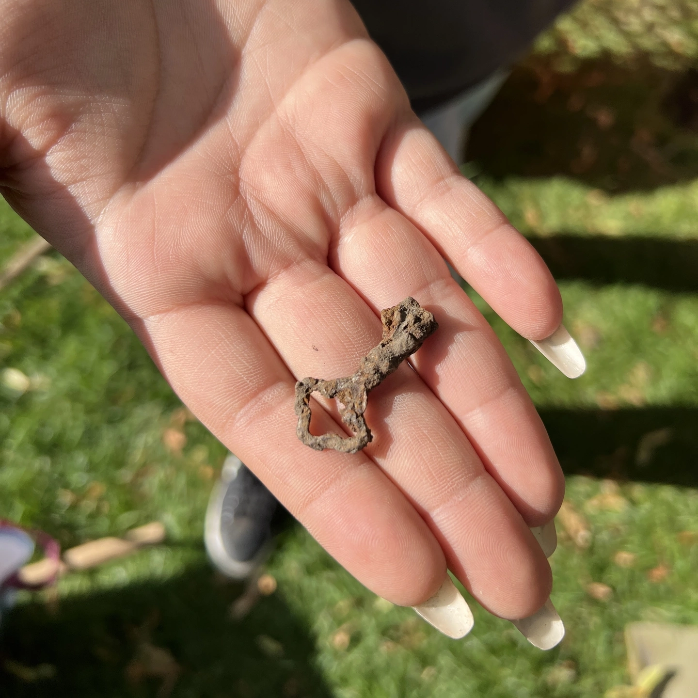 An open hand holds a small, ornate, rusted key.