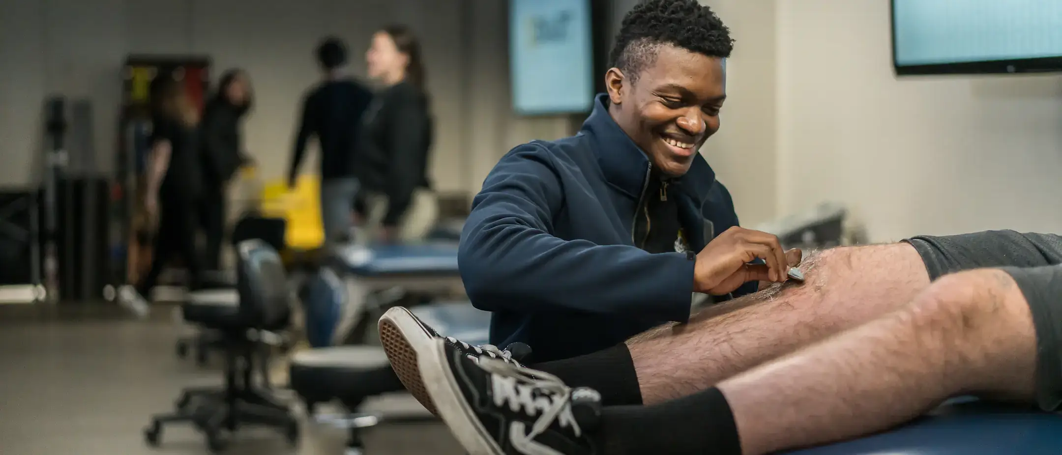 Athletic training student examines a knee of a patient.