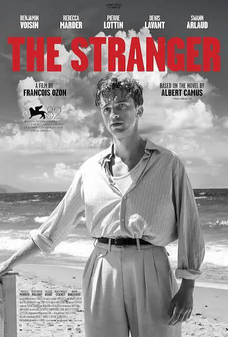 Black-and-white film poster of 'The Stranger,' featuring a man standing on a beach with the ocean in the background. Text includes credits and details of the film based on Albert Camus' novel.