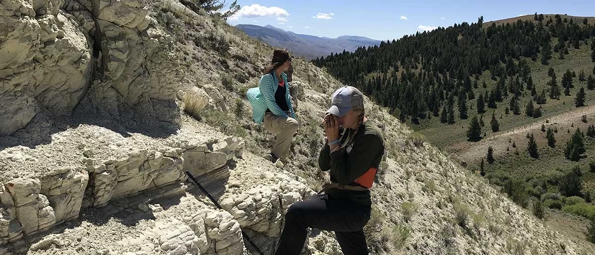 two people examing geological feature of an embedded rockface