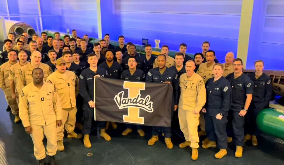  few dozen Navy soldiers singing while holding a Vandal flag. 