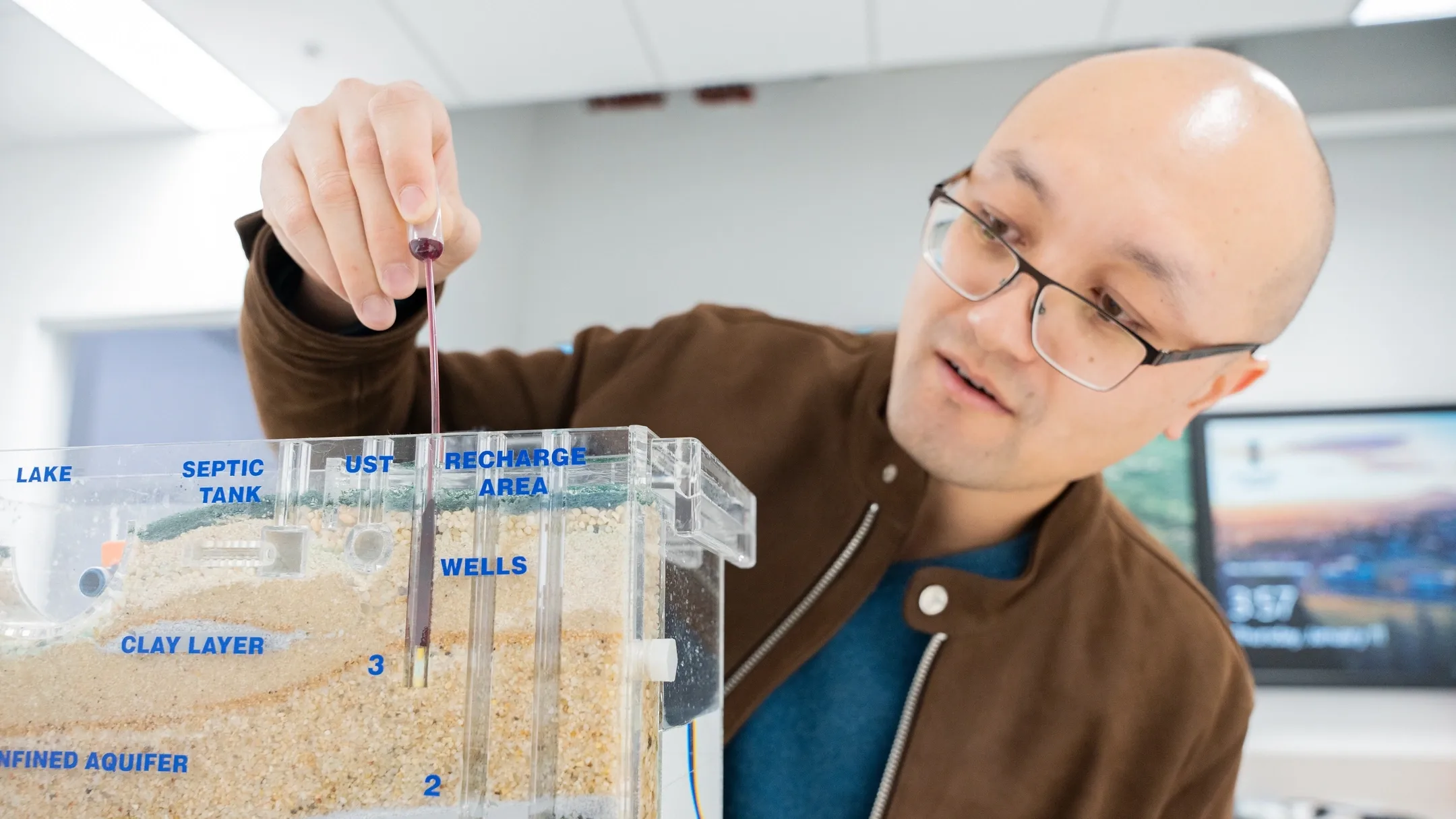 University of Idaho Earth and Spatial Sciences assistant professor  Meng Zhao studies how trees use water in relationship to how much water is available to human beings in relationship with climate change. Here, he is demonstrating a Sand and Gravel ground water Simulator.