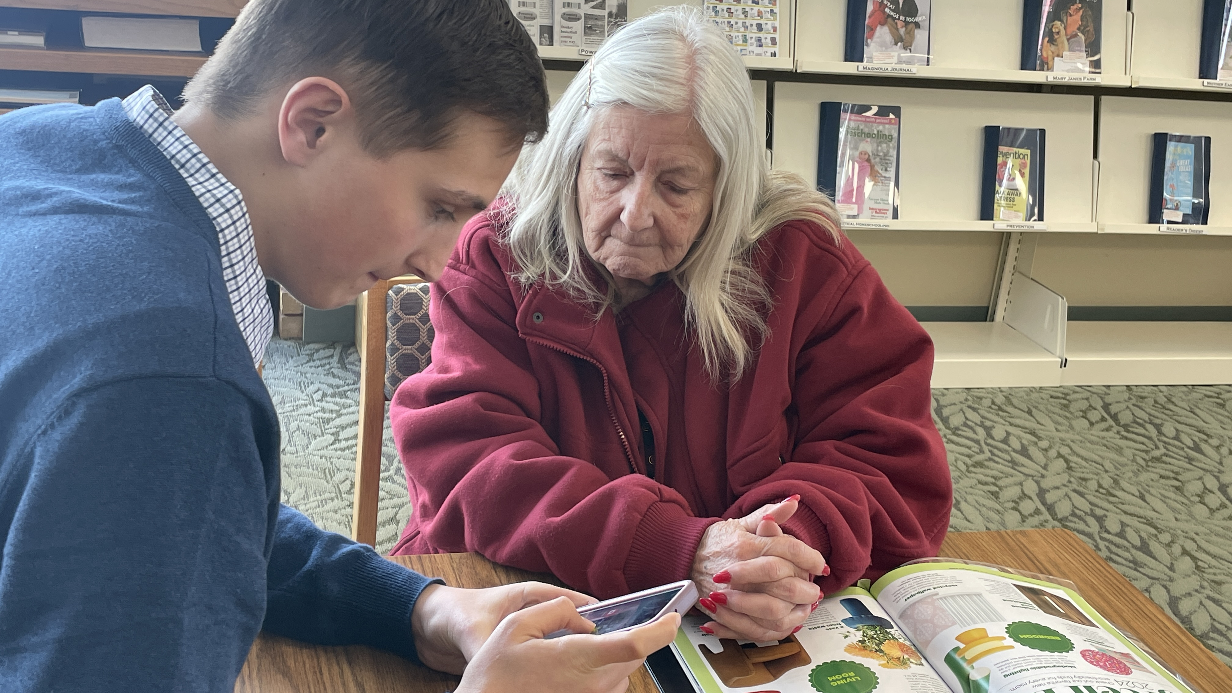A young man showing a elderly woman his cell phone.