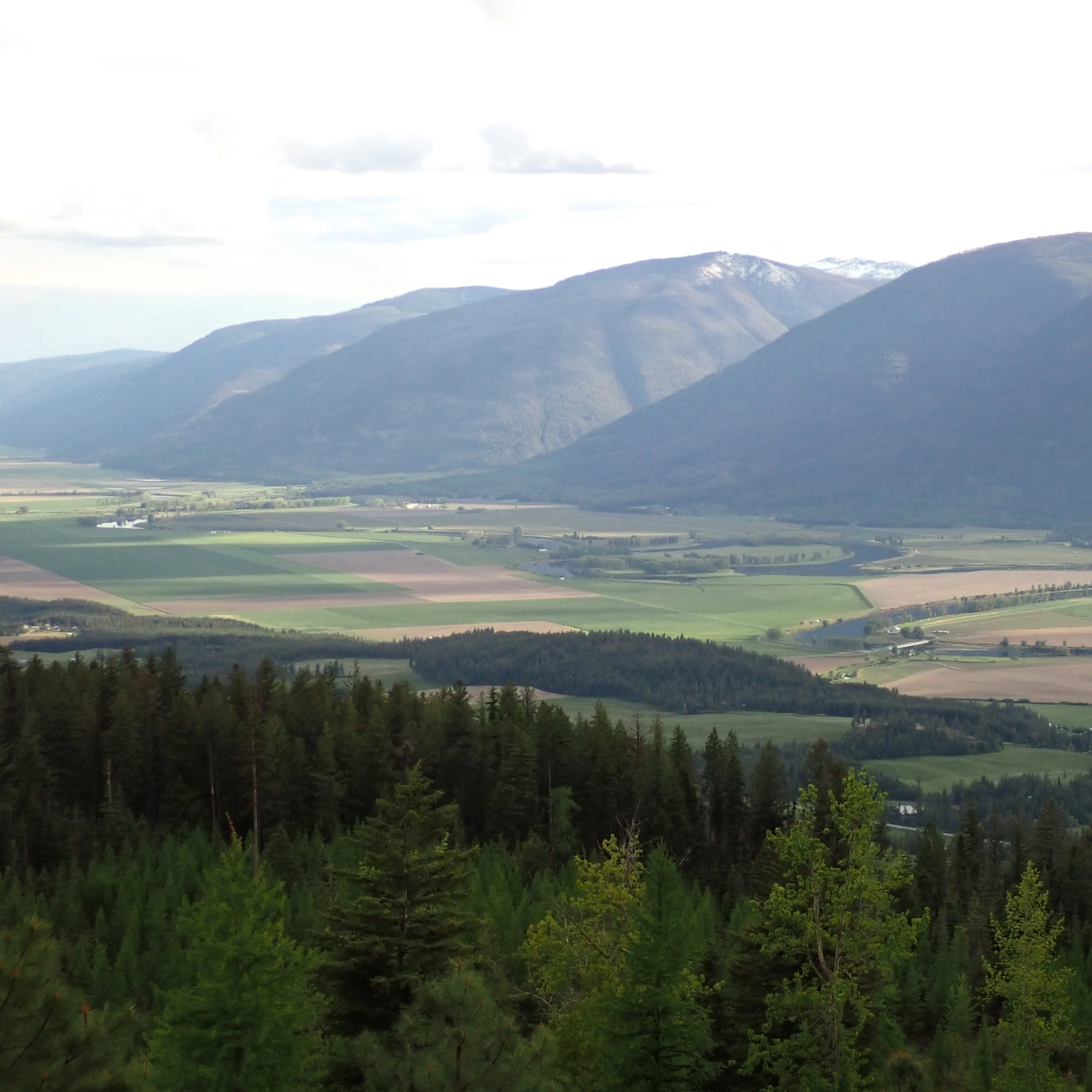 Farmland between two forested hills.
