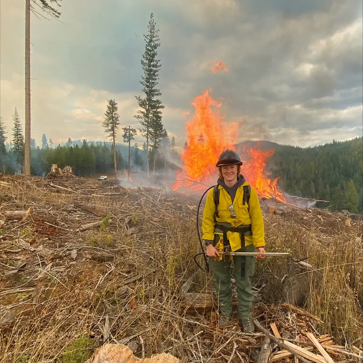 Eika Willis in firefighter gear standing in a burning field.