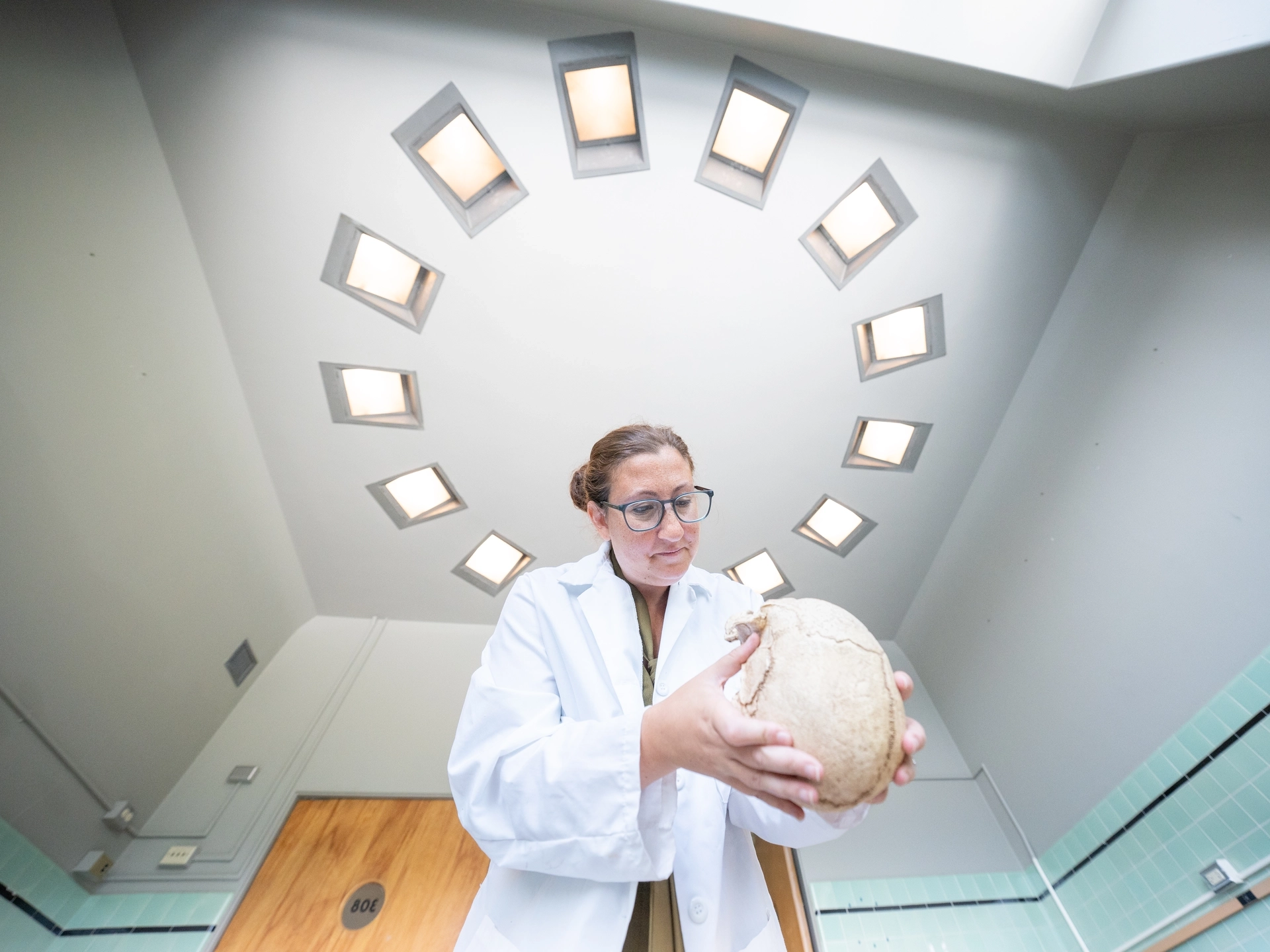 Woman in lab coat examines a human skull