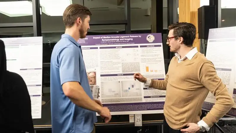 Graf Kirk speaks with a man in front of his poster.