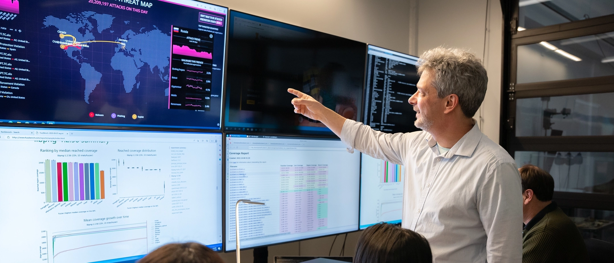 Man pointing to several screens full of data