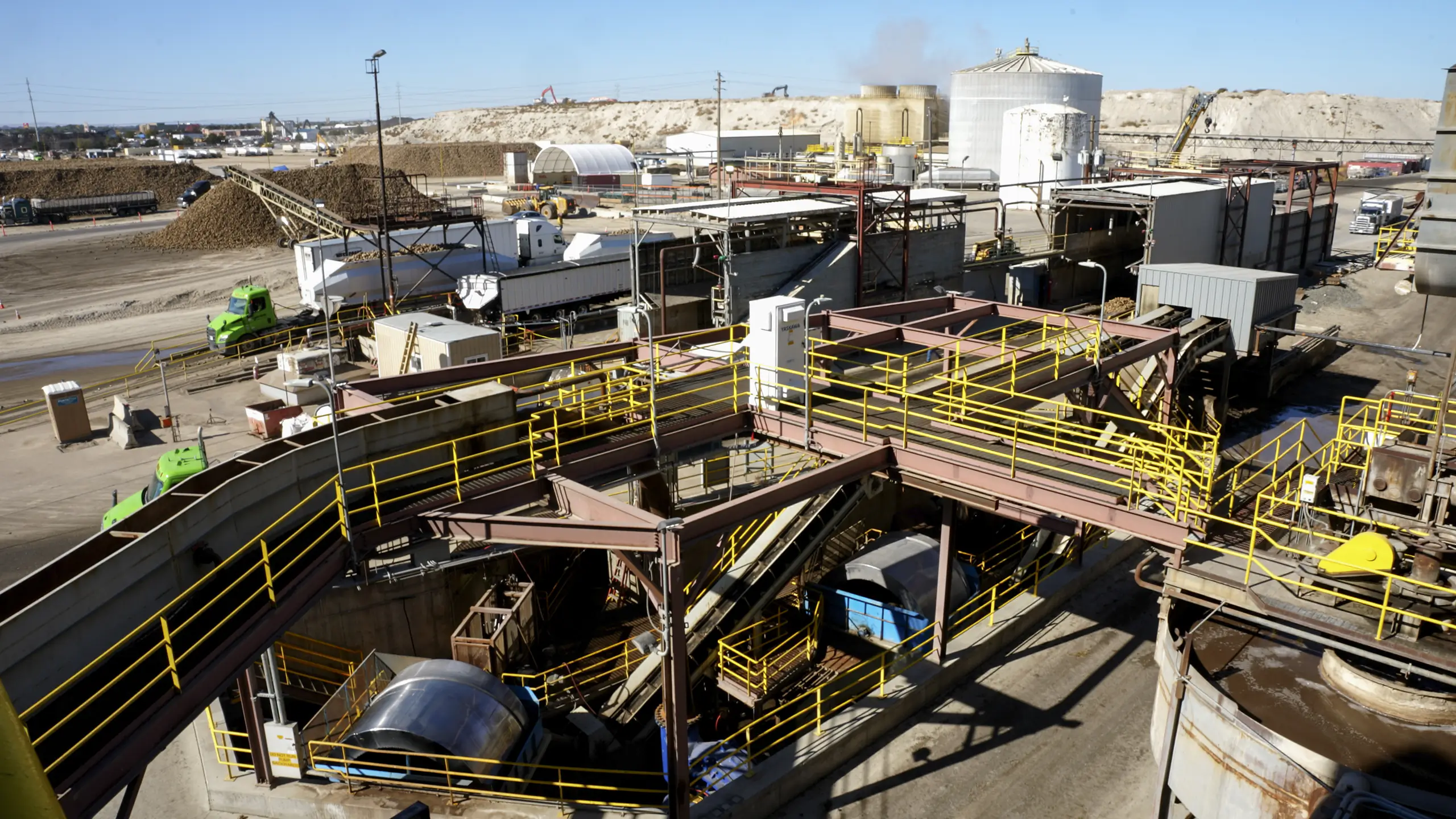 Exterior shot of a sugar factory's buildings, stairways and mounds of sugar beets.