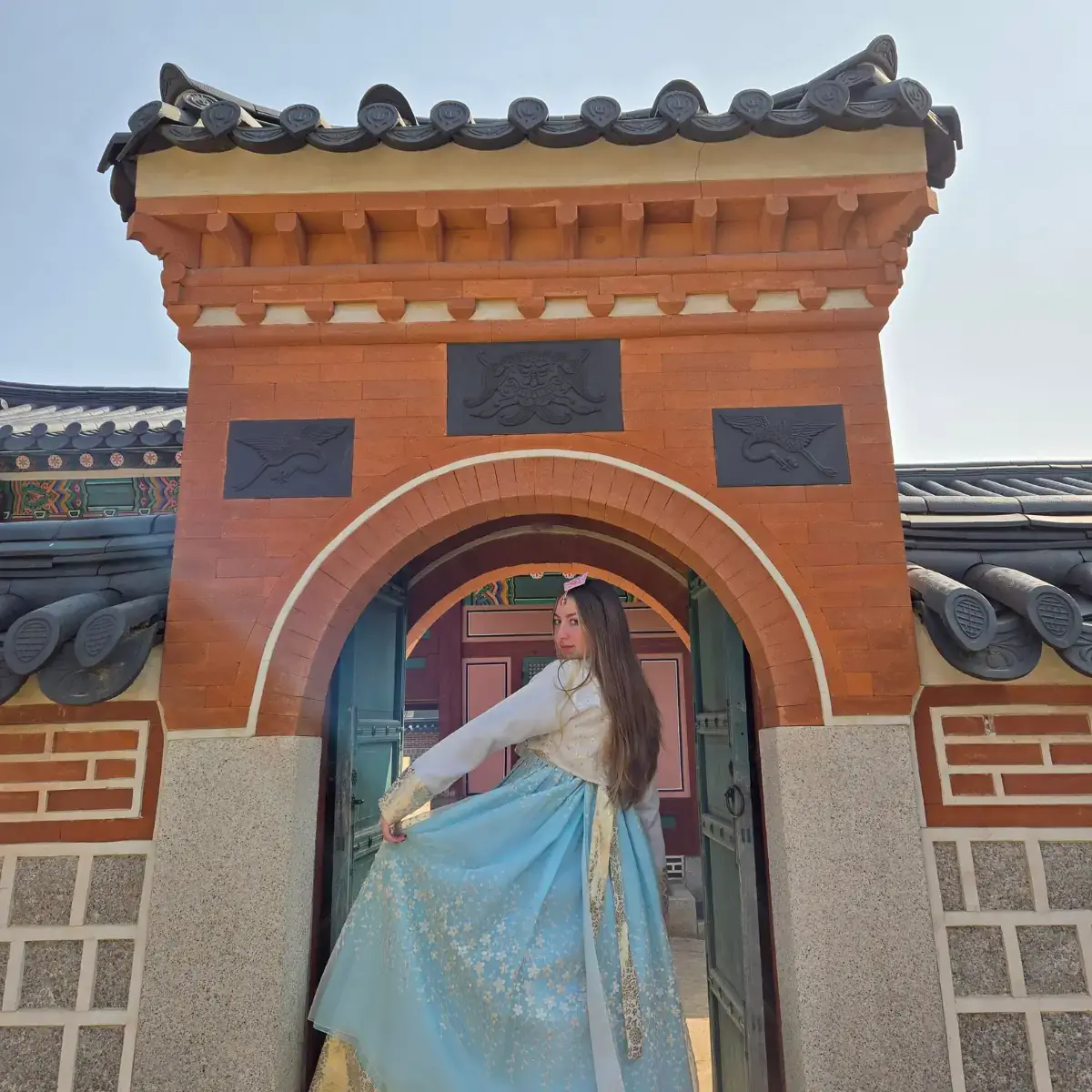 A woman holding the skirt of her dress out in front of an entrance.