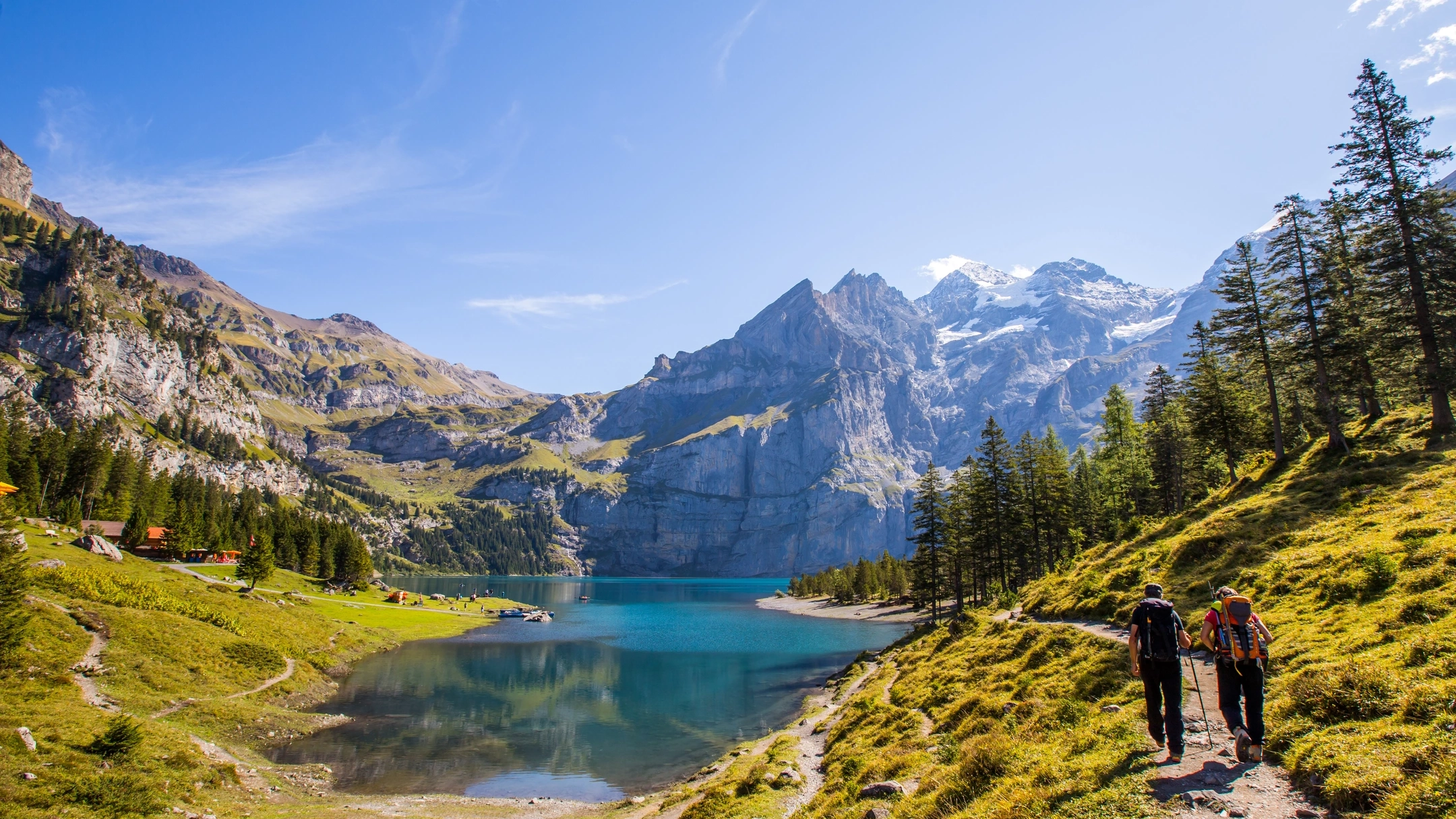 Panoramic summer view over Oeschinen lake with surrounding valley and walking path.