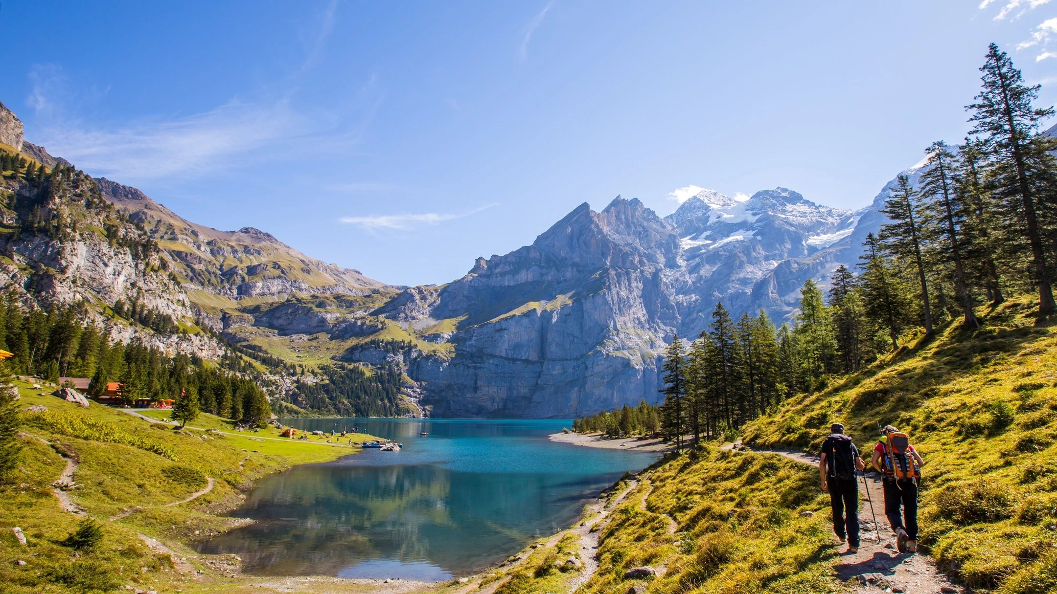 Panoramic summer view over Oeschinen lake with surrounding valley and walking path.