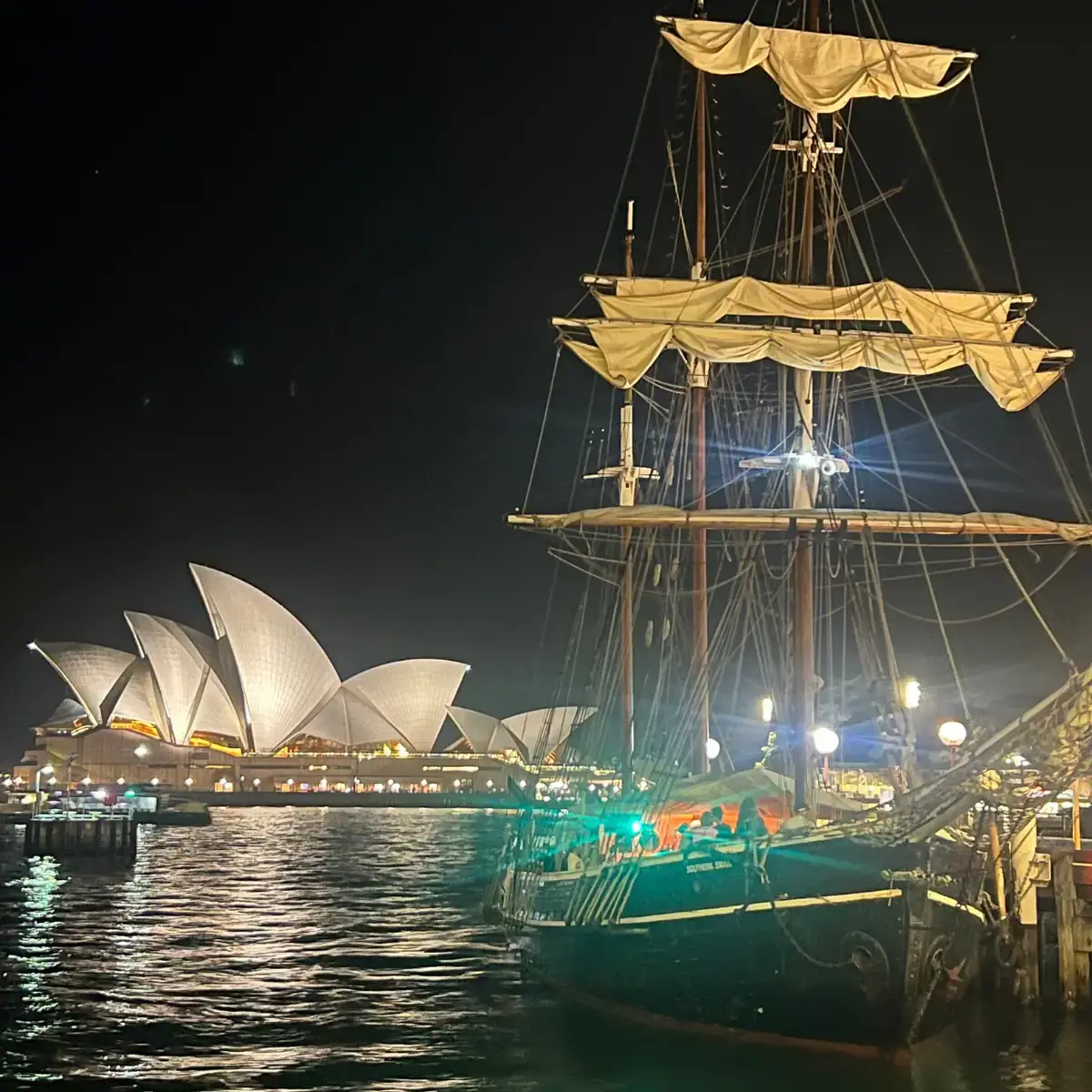 A sail boat sitting in front of the Sydney Opera House.