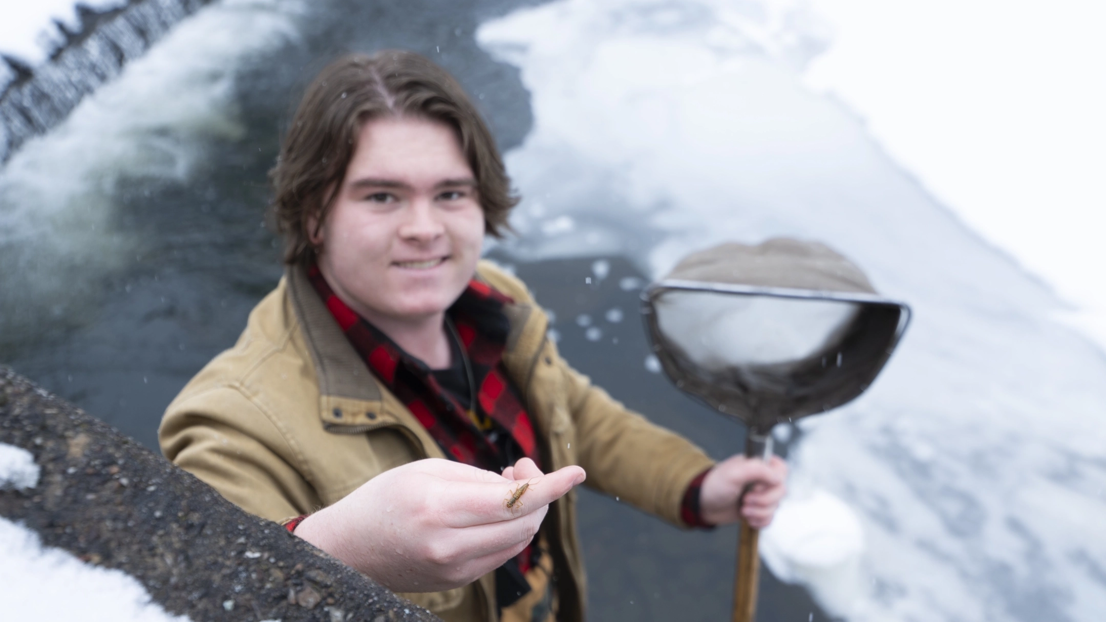 Jack Stafford stays near an icy pond, with a stonefly on his hand