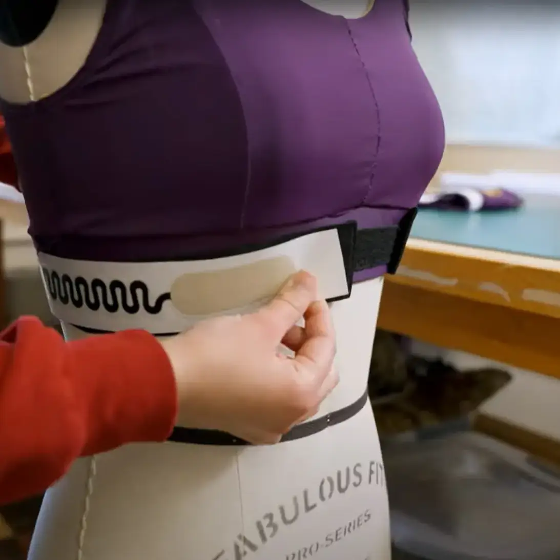 A woman applying a biosensor to a bra top