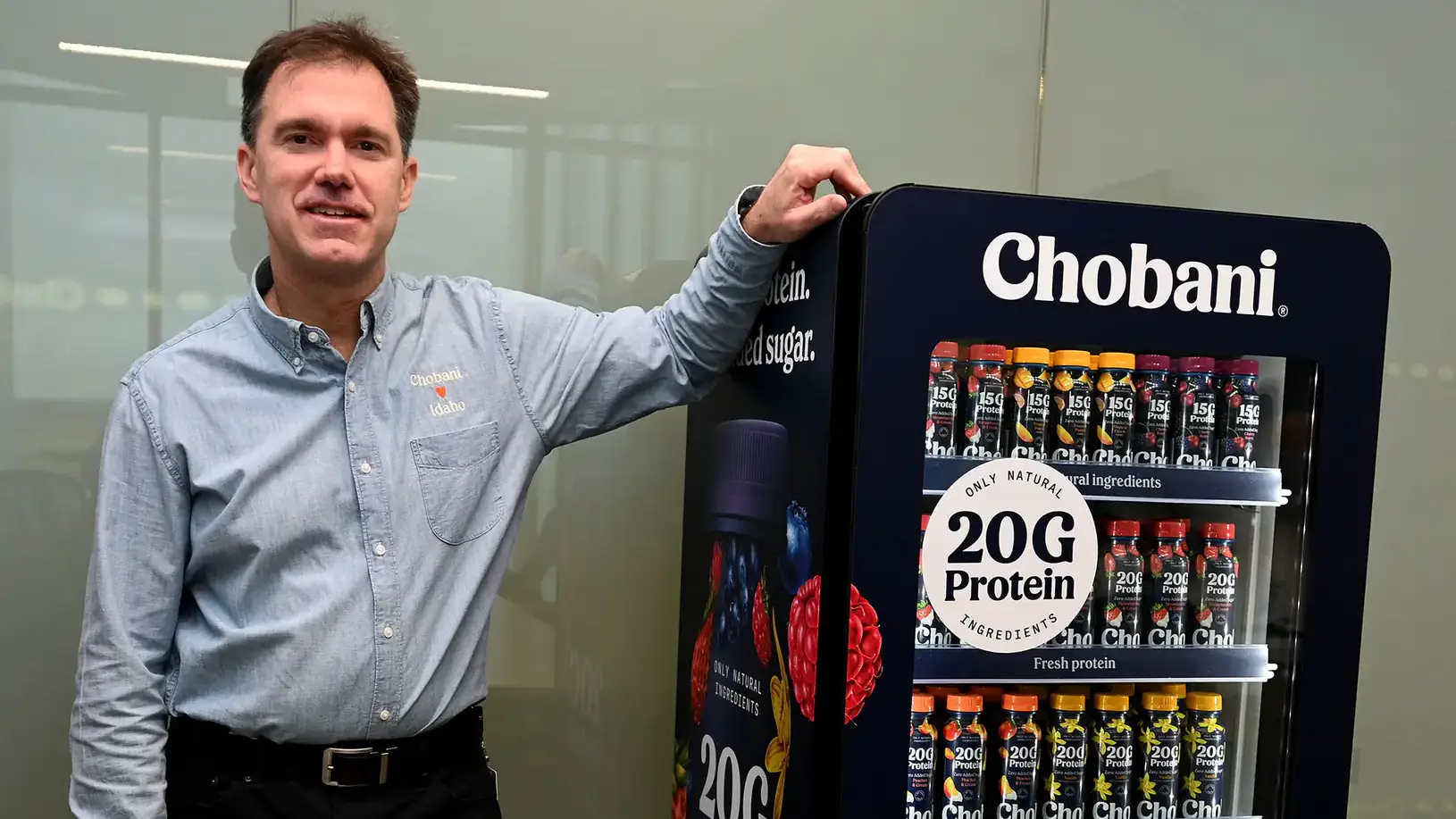 Peter Krell rests his arm on refrigerator filled with yogurt.